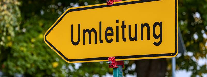 Ein gelbes Umleitungsschild, das in die linke Richtung zeigt.